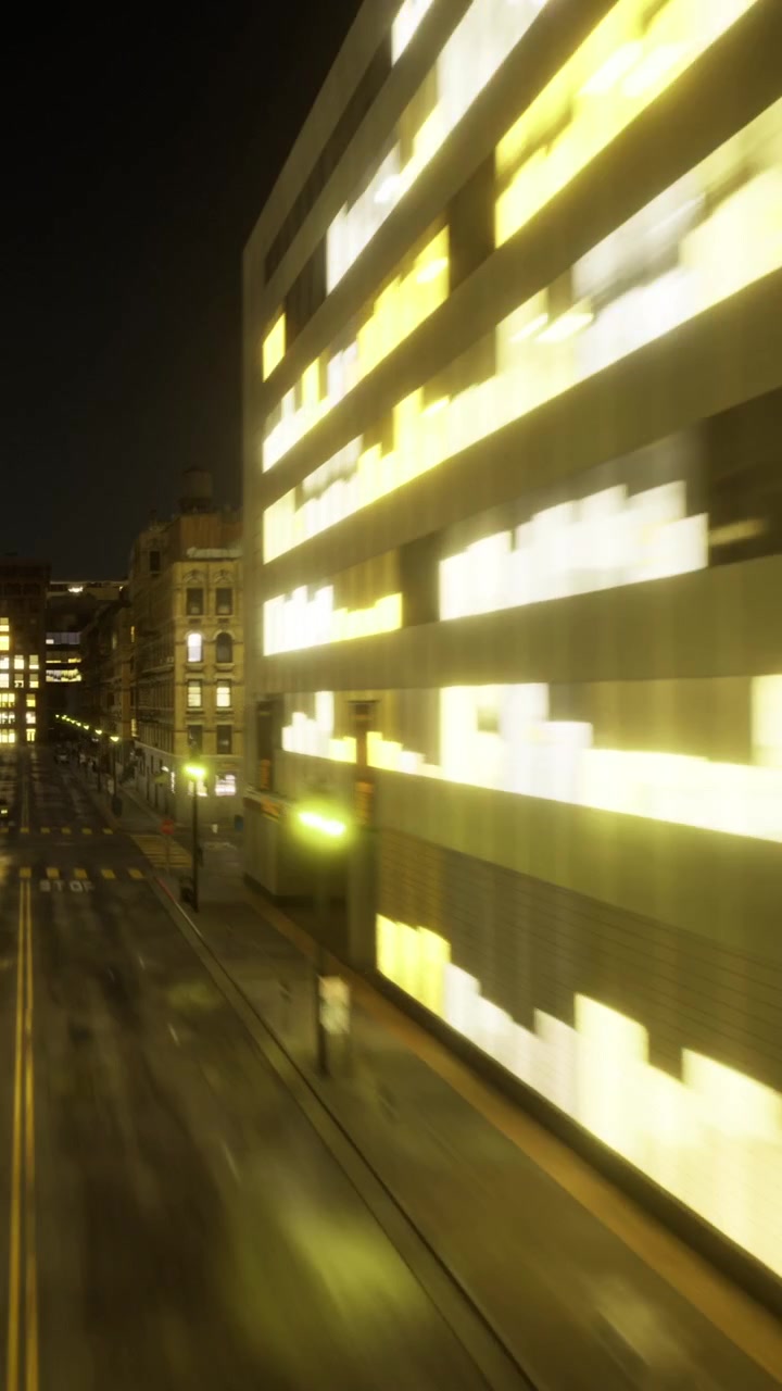 Vista noturna da rua com edifícios iluminados e carros em movimento