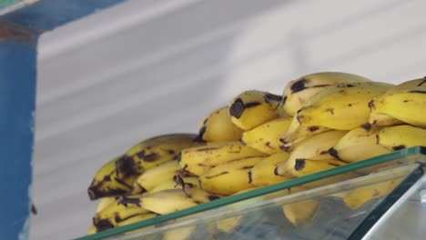 Handheld-shot-of-a-stack-of-bananas-over-a-glass-shelf-being-offered-at-a-fruit-store,-Costa-Rica