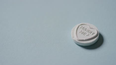 로맨틱한 메시지와 함께 심장 사탕을 손에 들고 파란 배경에서 나와 결혼해 주세요