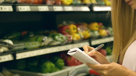 woman checking her list while grocery shopping