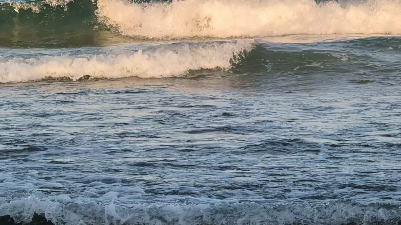 Onde che si infrangono contro la riva sabbiosa nel Mar Nero con risacca e schiuma bianca. Il movimento costiero naturale crea un'atmosfera marittima dinamica lungo la costa bulgara