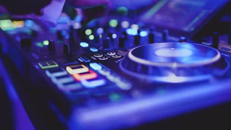 dj hand mixing music at a party on colorful mixing board, close up