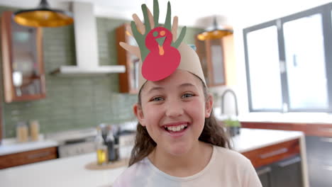 Happy-biracial-girl-with-paper-band-on-head-standing-and-smiling-in-sunny-living-room