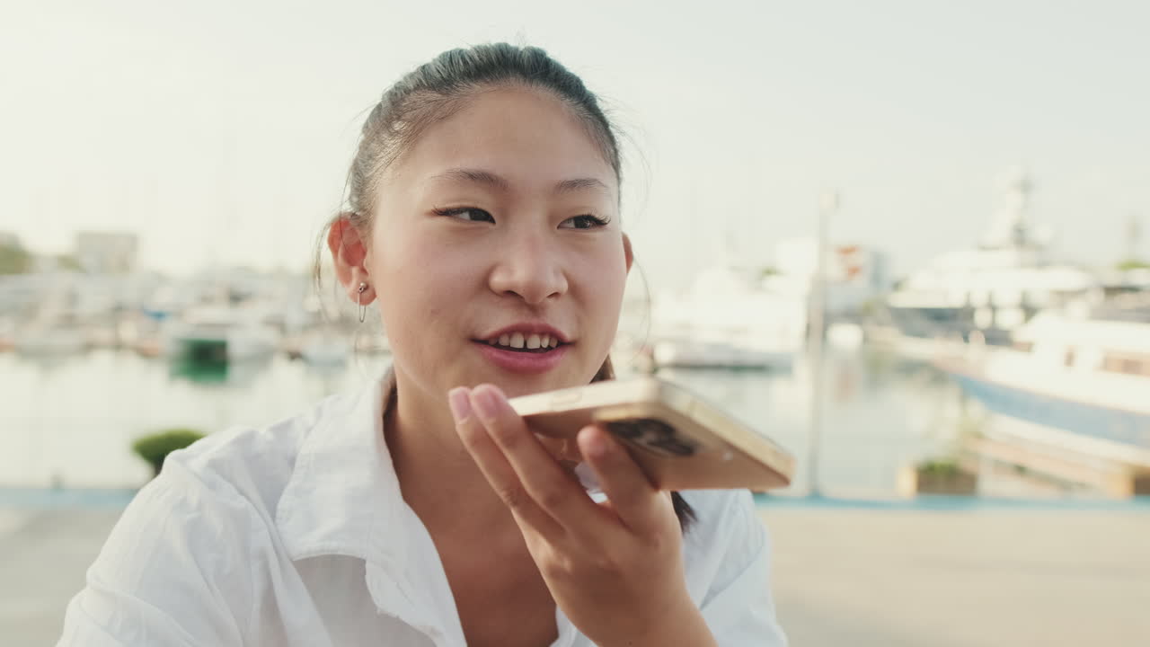 Asian woman using phone near waterfront