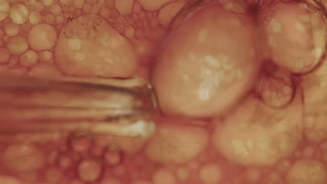 Macro-shot-of-a-syringe-filling-and-amber-liquid-with-air-creating-small-bubbles