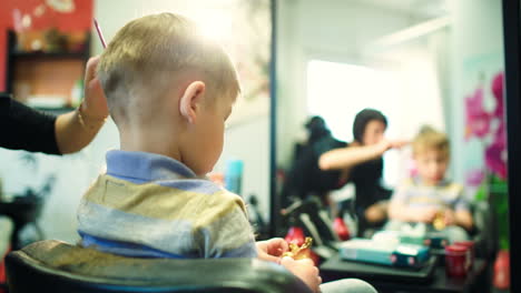 Peluquero-Cortando-El-Pelo-De-Un-Niño-Mientras-Juega-Con-Un-Juguete