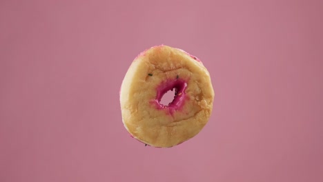 pink frosting donut with sprinkles at pink background. flying sweet dessert.