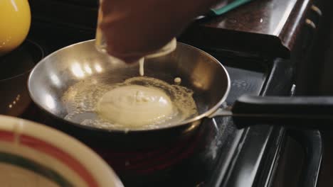 verter la masa de panqueques usando una jarra de vidrio en la sartén caliente - toma de primer plano