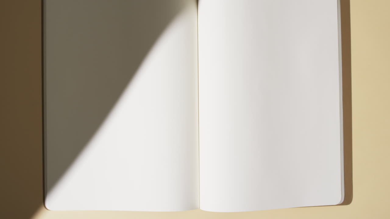 Video di un'ombra su un libro con pagine bianche vuote e spazio per il testo su sfondo giallo