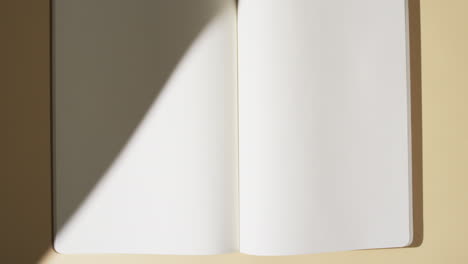 video of shadow over book with blank white pages and copy space on yellow background