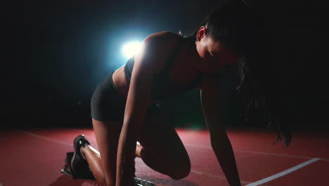 Female-athlete-on-a-dark-background-to-run-the-sprint-of-the-cross-country-pad-on-the-treadmill-on-a-dark-background