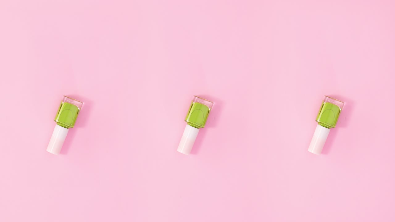 Three nail polishes bottles rotate on pastel pink background. Stop motion
