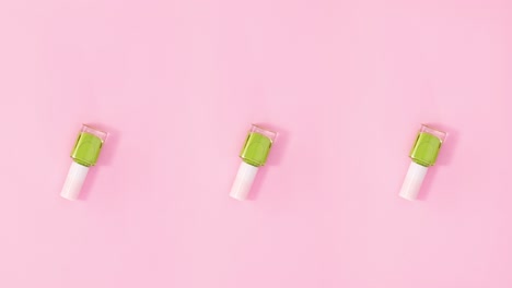 three nail polishes bottles rotate on pastel pink background. stop motion