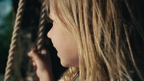 Close-up-of-little-girl-swinging-in-summer-day.