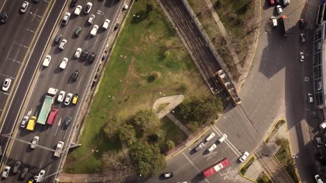 Aerial-top-view-showing-driving-tram-and-cars-on-highway-in-Buenos-Aires-at-sunset