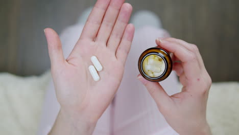 persona que sostiene pastillas y frasco de pastillas