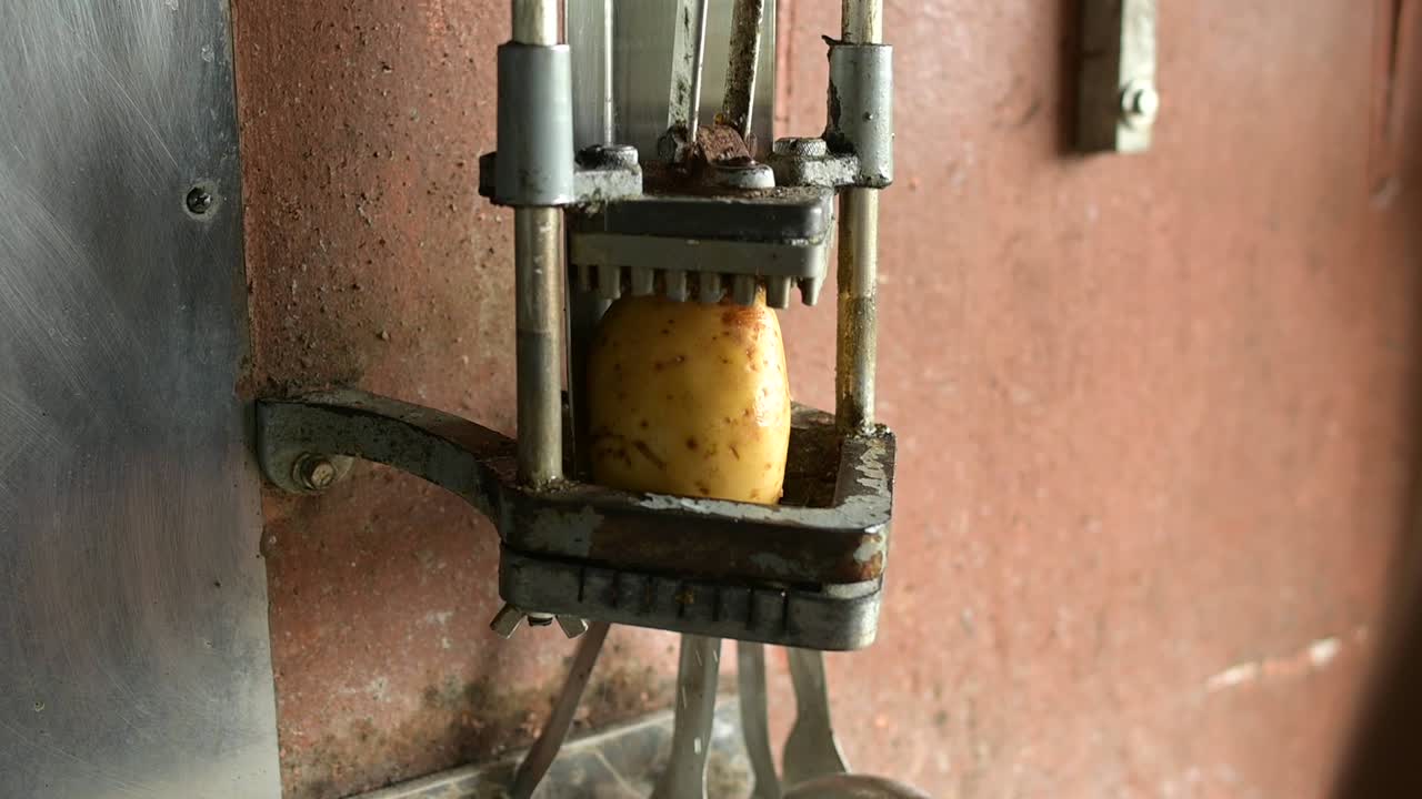 cocinero de cultivos que utiliza un cortador de patatas para preparar papas fritas