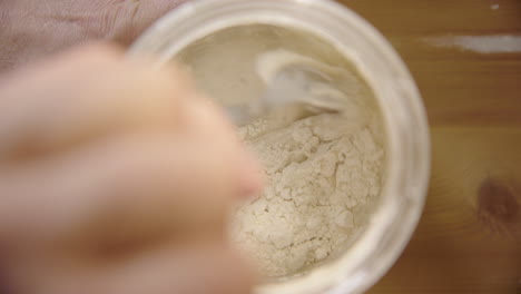 top down - sourdough starter is mixed with a spoon after being fed