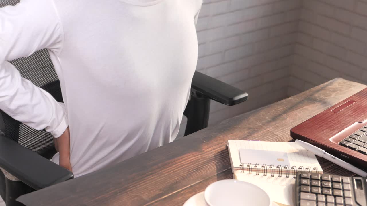 hombre que sufre de dolor de espalda mientras trabaja en su escritorio