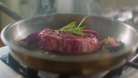 seasoned steak with herbs cooking in kitchen pan