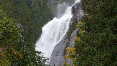 Powerful-Waterfall-Flowing-Down-From-Steep-Rugged-Mountains-In-Lush-Forest