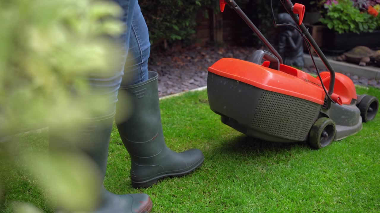 Garden lawn mower on green grass focus pull from bush welly boots appear