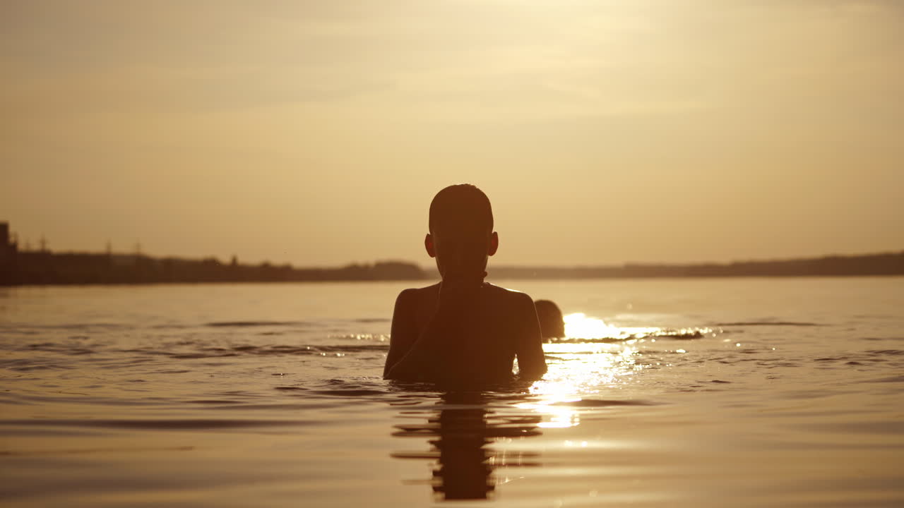 Children dive into water at beautiful sunset. Two boys diving underwater at the same time in calm river in the evening. Healthy lifestyle.