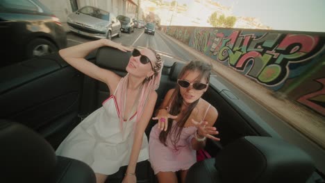 two women enjoying a convertible ride in the city