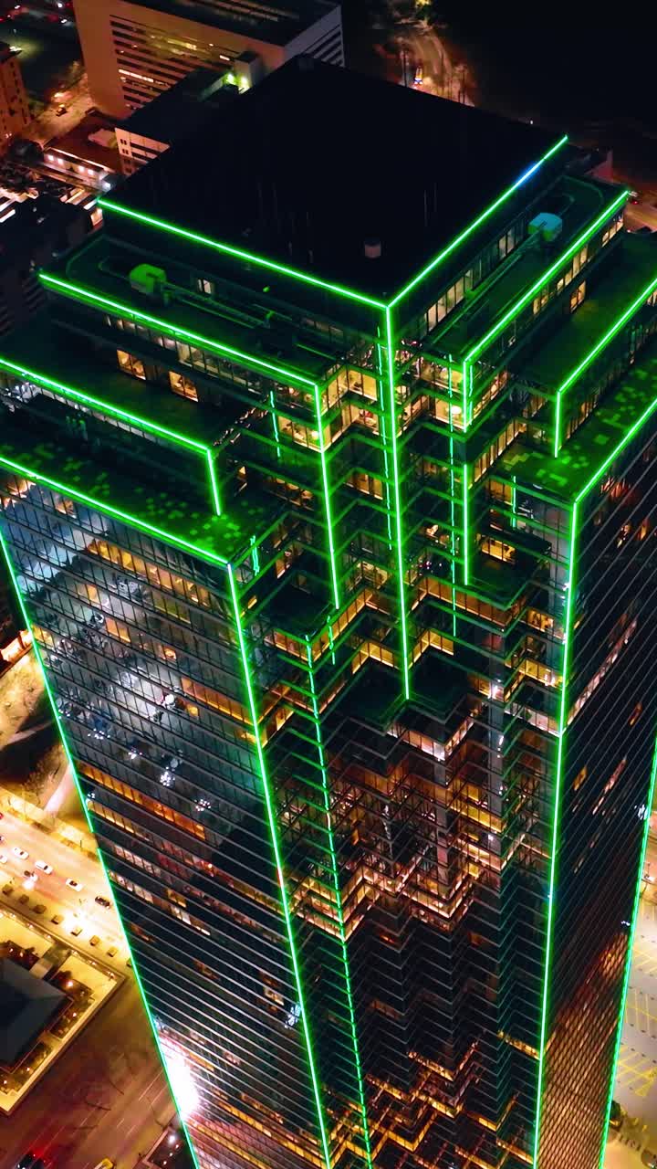 Destaque verde no edifício do Bank of America em Dallas, Texas, EUA à noite. Imagens de drone no topo do belo arranha-céu. Vídeo vertical.