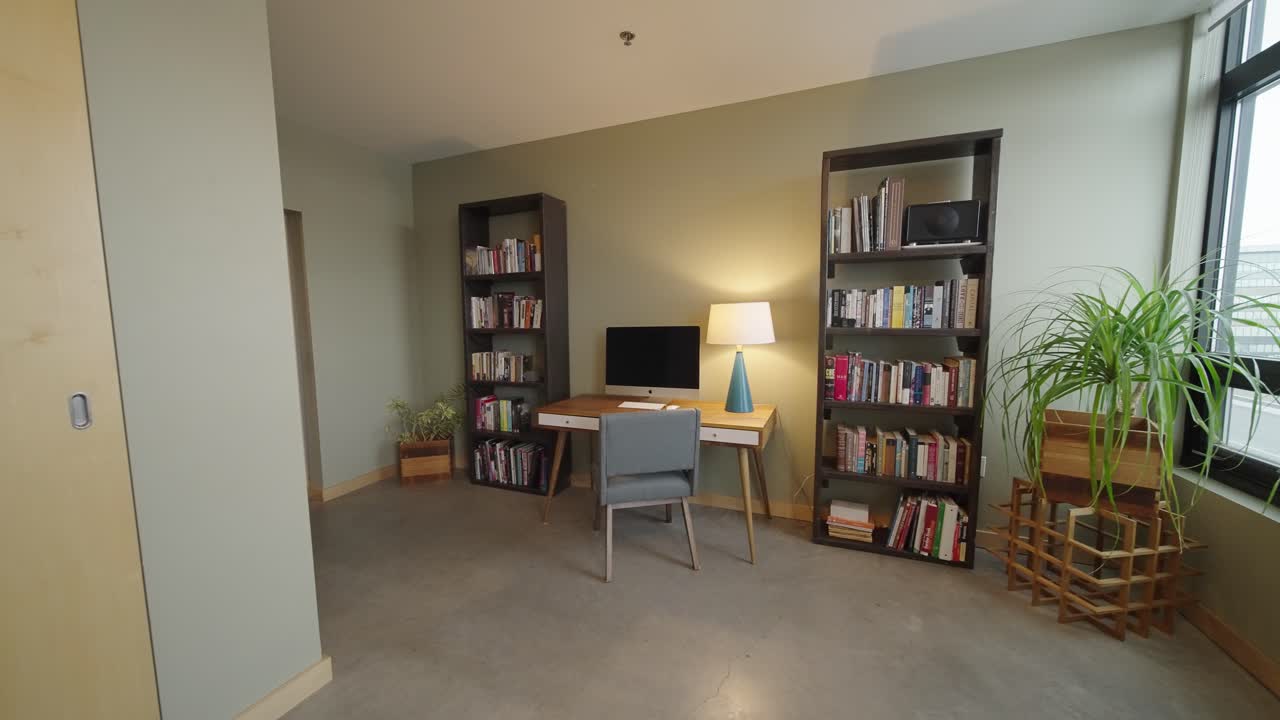 oficina con estantes de libros en un moderno edificio de condominios con escritorio y silla