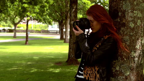 pretty redhead taking a photo in the park