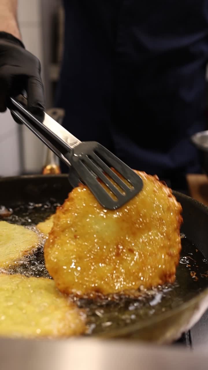 Kok steger gyldne kartoffelpandekager i varm olie