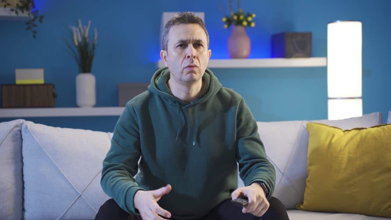 un hombre maduro viendo televisión en casa está asombrado por lo que ve en la pantalla.