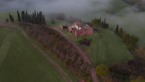 Ruinen-Eines-Bauernhauses-Auf-Einem-Abgelegenen-Ländlichen-Hügel-In-Der-Toskana-Während-Eines-Nebligen-Morgens,-Luftaufnahme