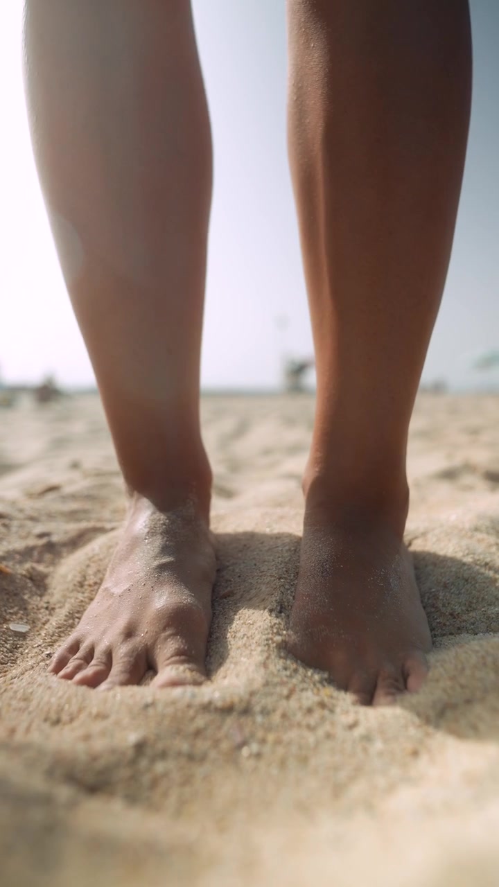 Primo piano di piedi che giocano nella sabbia calda della spiaggia