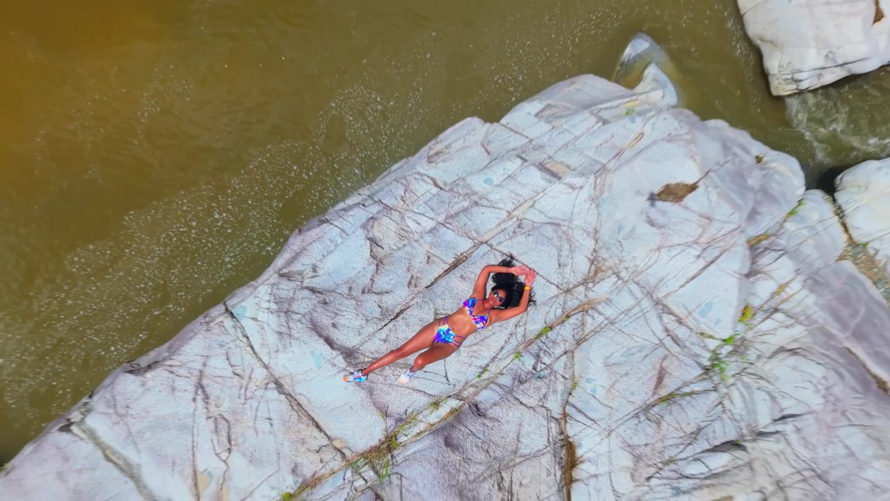 A cinematic drone flyover of a girl in a bikini exploring the dramatic, sun-drenched canyons of Cañón Blanco, Puerto Rico.