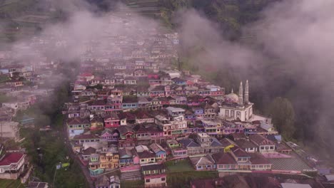 Tilt-up-shot-of-village-Nepal-van-Java-during-sunrise-with-low-clouds,-aerial