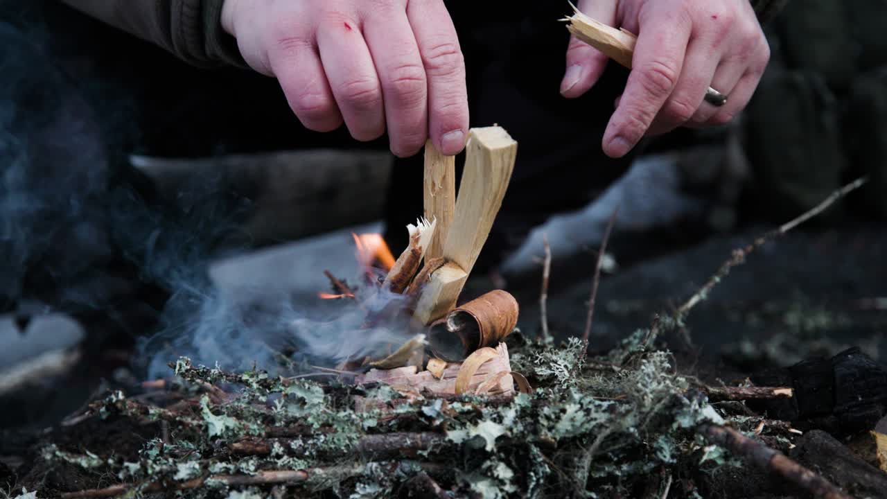 Man starting campfire and breaking twigs, slow motion close-up