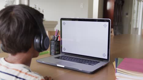 Niño-Birracial-Aprendiendo-En-Línea-En-La-Mesa-Usando-Una-Computadora-Portátil-Con-Espacio-Para-Copiar-En-La-Pantalla,-Cámara-Lenta