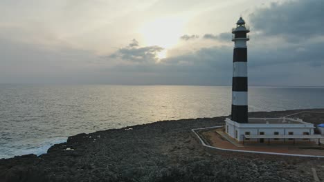 puesta de sol sobre el faro de artrutx en menorca españa