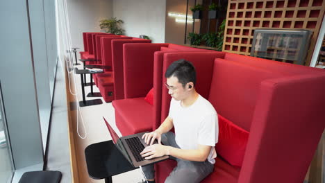 asian freelance worker working in empty co-working space with his laptop