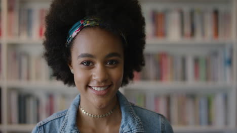 portrait beautiful young african american woman smiling happy enjoying successful education lifestyle afro hairstyle slow motion bookshelf background