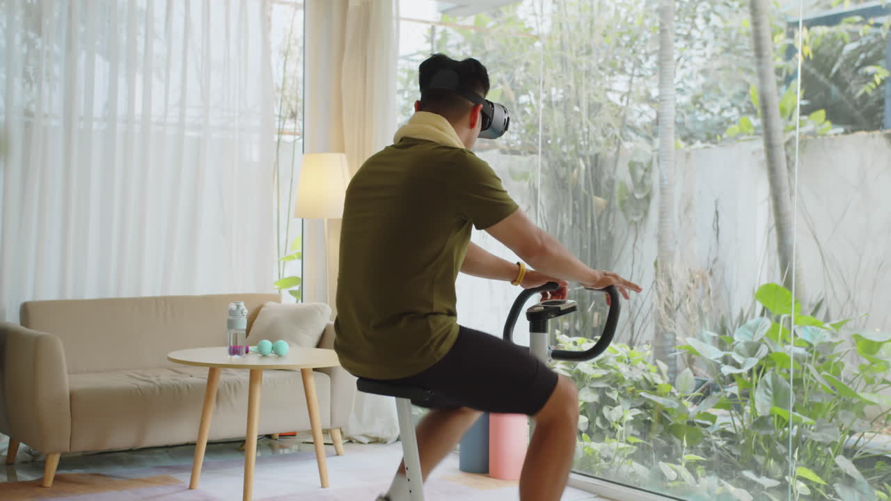 Sporty Man Wearing VR Headset when Training on Fitness Bike