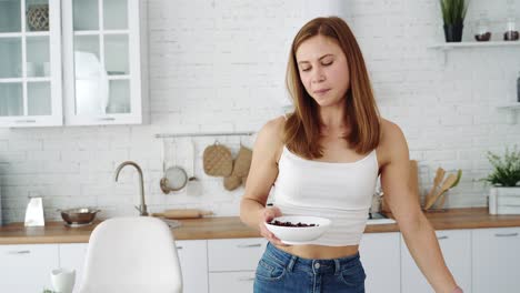 the girl in the kitchen eats granola from a plate for breakfast. healthy vegetarian diet food
