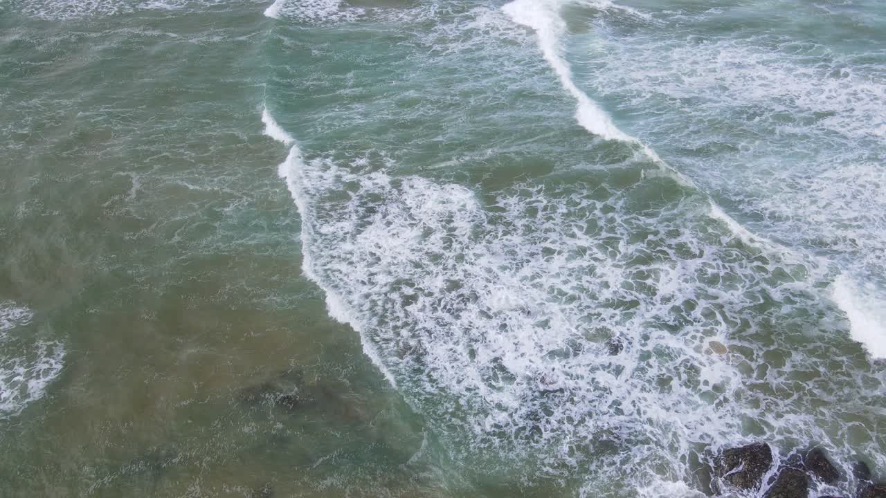 olas espumosas blancas rompiendo en el promontorio y rocas en la playa sawtell, costa norte de nueva gales del sur, australia