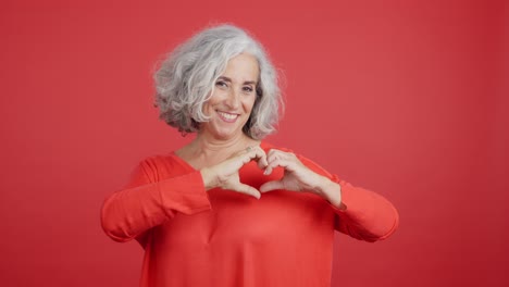 smiling senior woman making a heart shape with hands