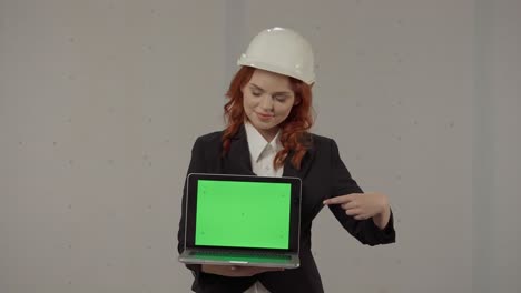 businesswoman presenting a laptop with green screen in construction site