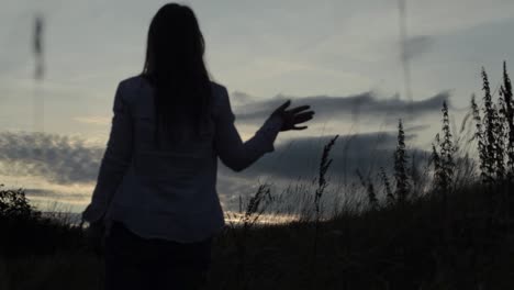 woman waving goodbye in a sunset