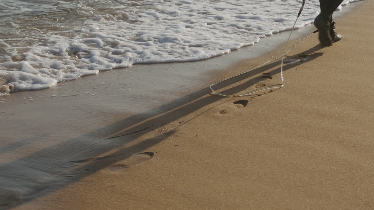 Surfer man walking to the beach at sunset preparing for surfing training and search for waves in Barcelona, spain, water, ocean exercise in sea with board, athletic male holiday or travel in vacation