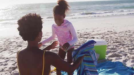 Video-of-happy-african-american-mother-and-daughter-hugging-on-beach